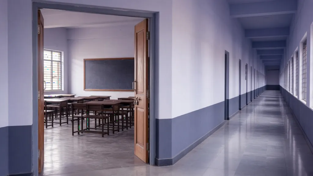 Empty classroom seen from an Indian private school corridor with wooden desks and soft morning light